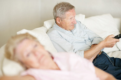 Old man watching television with wife at home