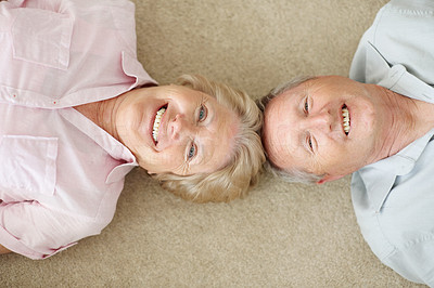 Happy old couple lying down head to head on the floor