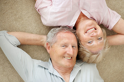 Old couple lying down on the floor with heads together