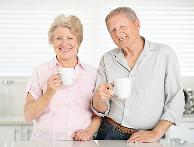Happy old couple drinking coffee together in kitchen