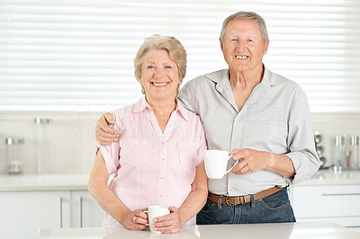 Sweet senior couple drinking coffee in the kitchen