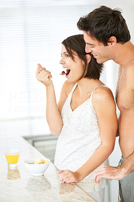 Young couple eating fruit salad in the kitchen