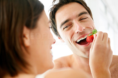 Pretty young female feeding strawberry to her husband