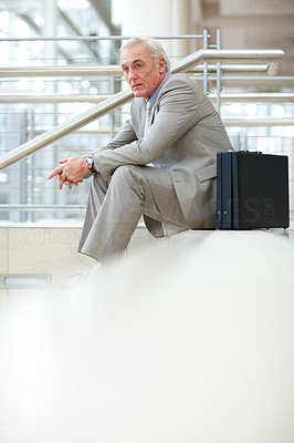 Senior businessman sitting on stairs outside a building