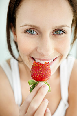 Closeup of a happy female holding a bitten strawberry