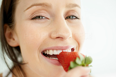 Closeup of a happy female biting onto a strawberry