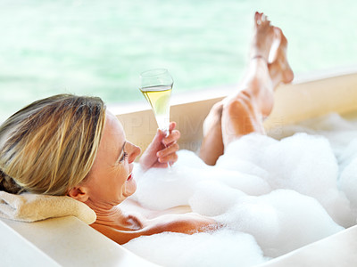 Middle aged lady with glass of wine in the bathtub