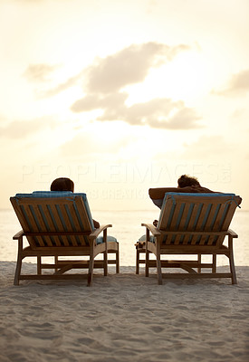 Couple relaxing at seashore in beach chairs