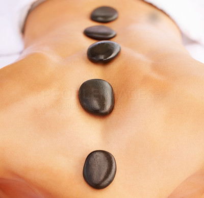 Stone massage therapy - Closeup of a woman with rocks on her spine