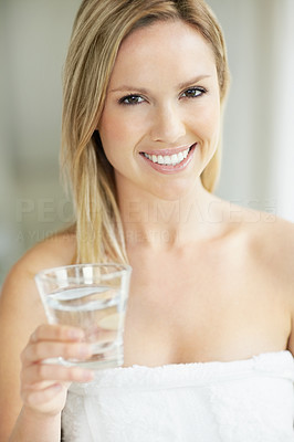Cute woman wrapped in towel and holding a glass of water