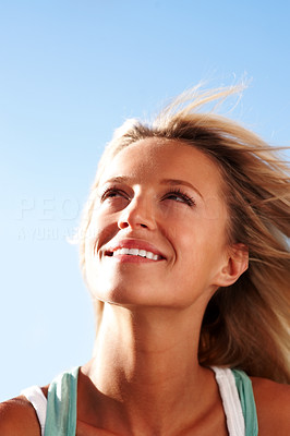 Cute young lady looking upwards against sky