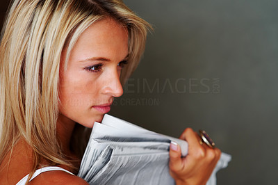 Cute young woman thinking while holding newspaper