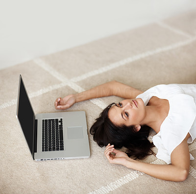 Top view of a lovely female lying on the floor besides a laptop