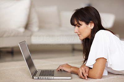 Lovely young female lying on the floor using a laptop