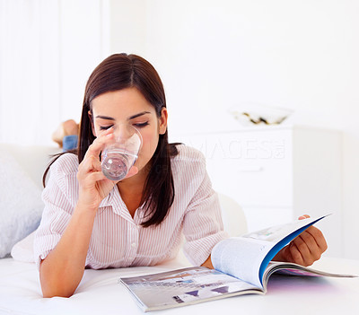 Beautilful woman drinking water and reading a magazine