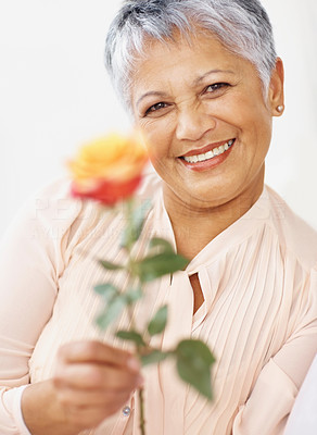 Happy elderly woman offering you a flower