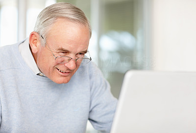 Happy elderly man working on a laptop