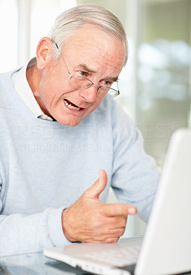 An excited mature man pointing towards laptop