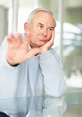 Sad mature man making stop gesture