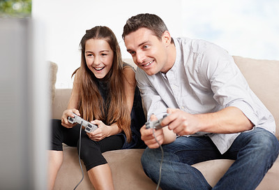 Happy father and daughter playing video games at home