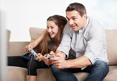 Playful daughter and father playing video games at home