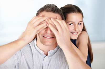 Cheerful little girl covering her father\'s eyes from behind