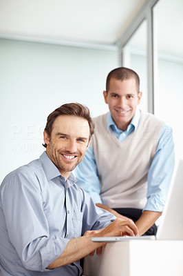 Two business executive smiling as he works on laptop