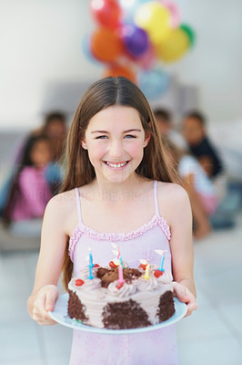 Cute little girl standing with a lit birthday cake