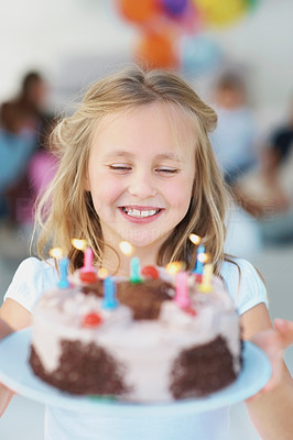 Little girl holding a birthday cake and making a wish