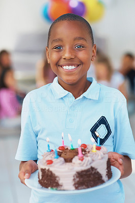 Black young kid standing with a lit birthday cake in hand