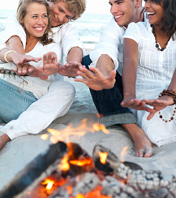 Young people sitting by bonfire at the beach