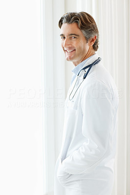 Smiling handsome doctor standing by the window