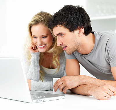 Happy young man and young woman sitting together and working on a laptop