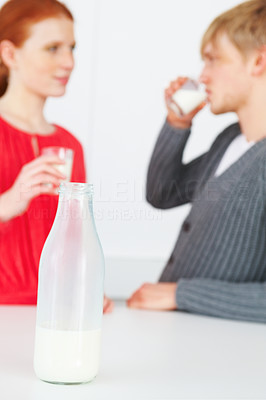 Closeup of a milk bottle with couple in the background