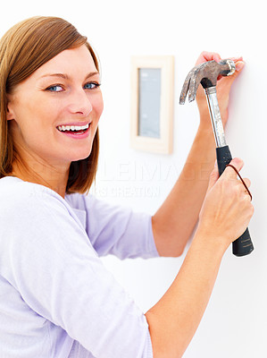 Closeup portrait of a happy girl using hammer on the wall