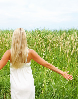 Rear view of a beautiful young lady standing in field
