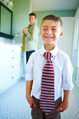 Father wearing a tie with his smiling son standing in the foreground