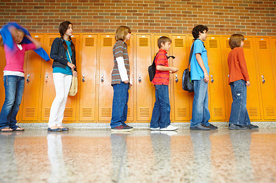 Young students standing in a line against cabinets in background
