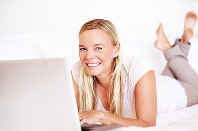 Pretty mature lady on bed with a laptop smiling