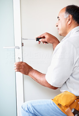 Experienced handyman fixing a lock on a door