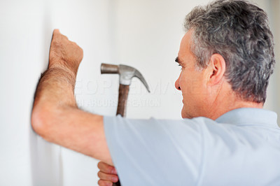 Mature man hammering a nail into the wall