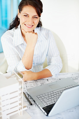 Happy female architect with building model and laptop at work