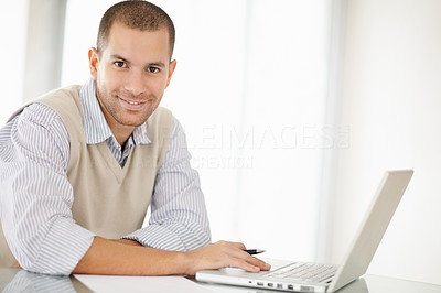Smiling middle aged man holding pen while working on a laptop