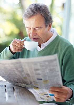 Retired old man reading newspaper in morning