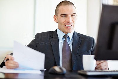 Middle aged business man with a document and looking at computer