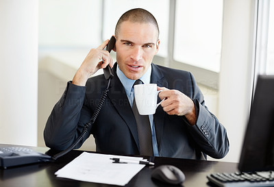 Middle aged business man using telephone and holding coffee mug