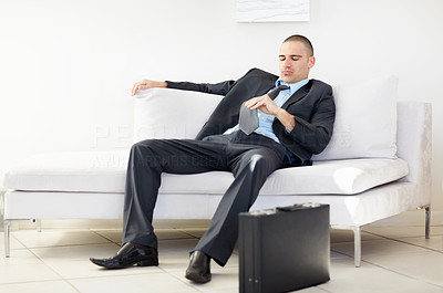 Middle aged business man sitting on sofa and looking at necktie