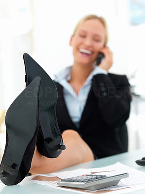 Business woman resting with legs on table and using phone at office