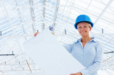 Happy lady architect holding blueprint at construction site
