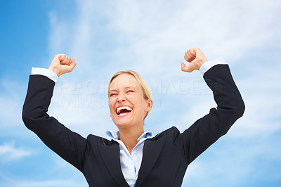 Business woman raising her arms in joy with sky in the background